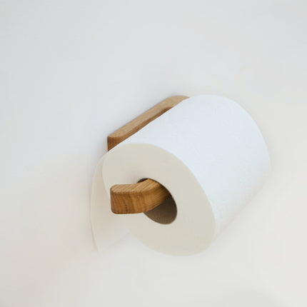 Detal drewnianego wieszaka na papier z naturalnego dębu z widocznym usłojeniem, wykończony w minimalistycznym stylu.