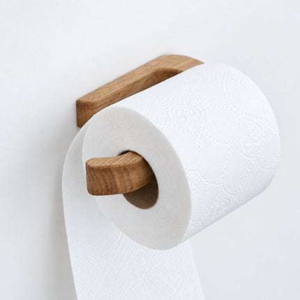 Nowoczesny samoprzylepny naturalny dębowy uchwyt na papier toaletowy na białej ścianie.