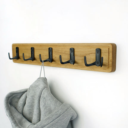 Zbliżenie na ozdobne frezowanie krawędzi dębowej podstawy wieszaka, podkreślające naturalne usłojenie drewna.