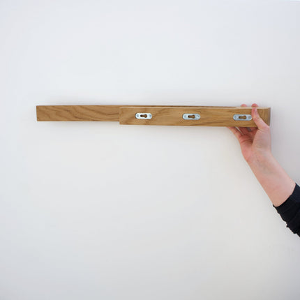 Minimalistyczny uchwyt na ręcznik z dębu, stanowiący elegancki akcent dekoracyjny w surowym, nowoczesnym wnętrzu.