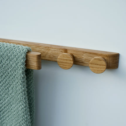 Zbliżenie na okrągłe dębowe gałki wieszaka, pokazujące precyzyjne wykończenie i aksamitną gładkość.