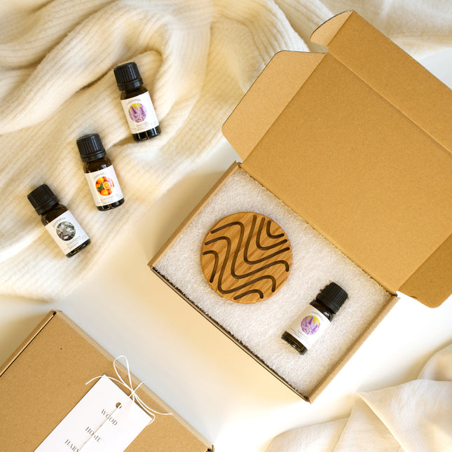 Dębowy dyfuzor zapachowy z wyżłobionymi rowkami obok buteleczki olejku eterycznego w estetycznym eko-kartoniku.